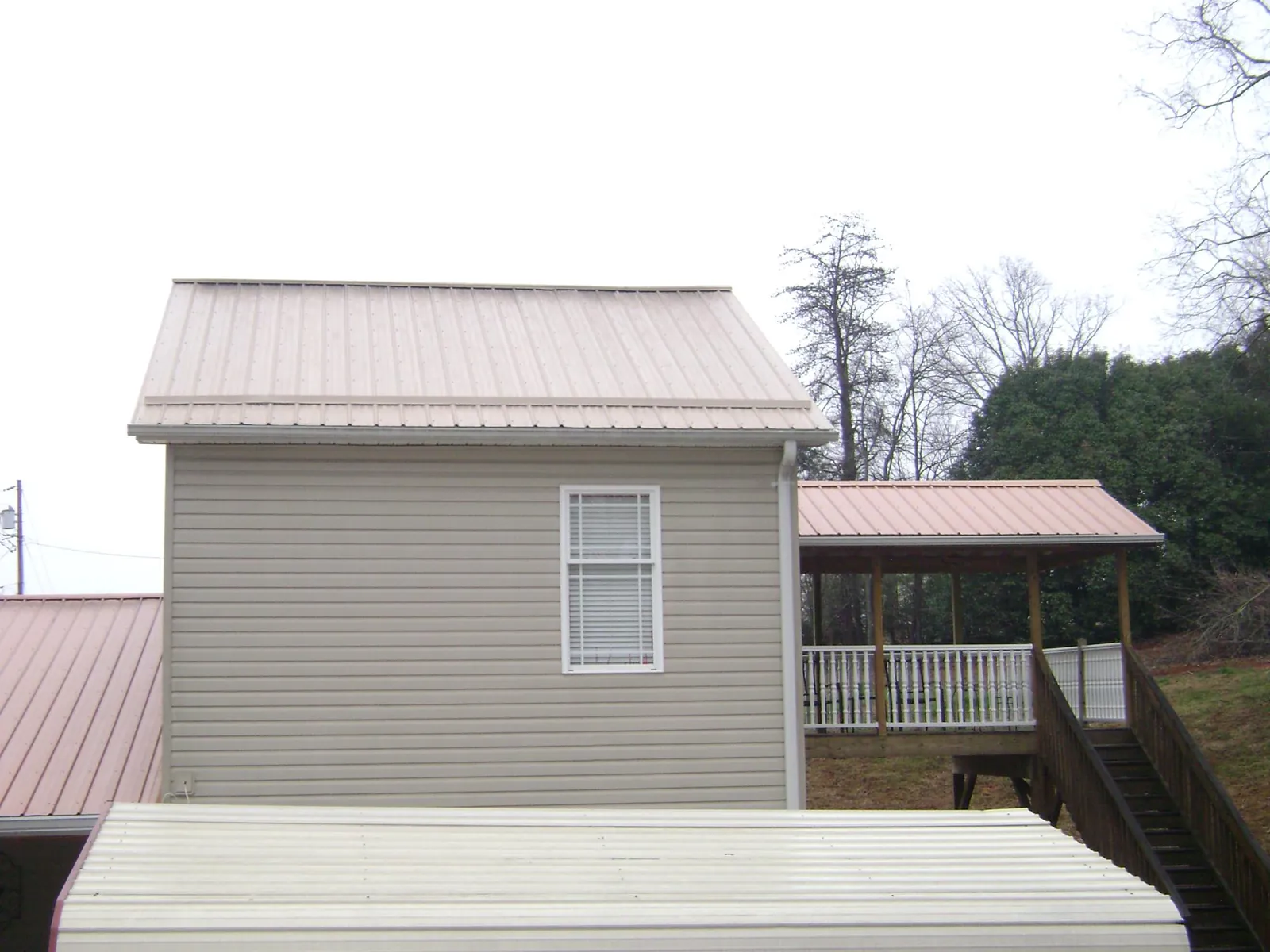 Tan metal roofs on a two story addition and attached porch, from a Roof Replacement job in Orlando